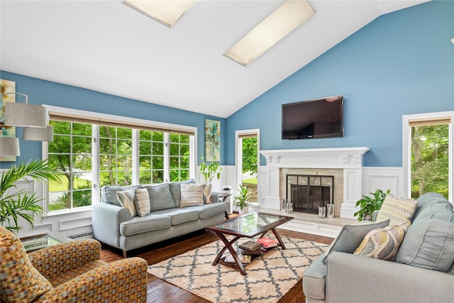 25 Cliff Rd W, Wading River, NY 11792 - living room featuring wood finished floors, high vaulted ceiling, healthy amount of natural light, a glass covered fireplace, and wainscoting
