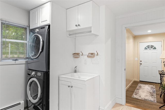 25 Cliff Rd W, Wading River, NY 11792 - washroom with stacked washer / drying machine, a baseboard heating unit, cabinet space, baseboards, and light wood-style flooring