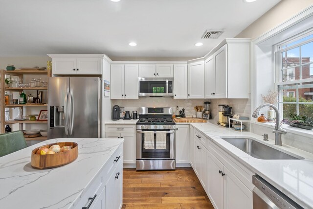 63 Liberty St, Beacon, NY 12508 - kitchen featuring stainless steel appliances, a sink, white cabinets, light wood-type flooring, and tasteful backsplash