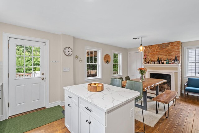 63 Liberty St, Beacon, NY 12508 - kitchen featuring light wood-type flooring, light stone countertops, white cabinets, a fireplace, and hanging light fixtures
