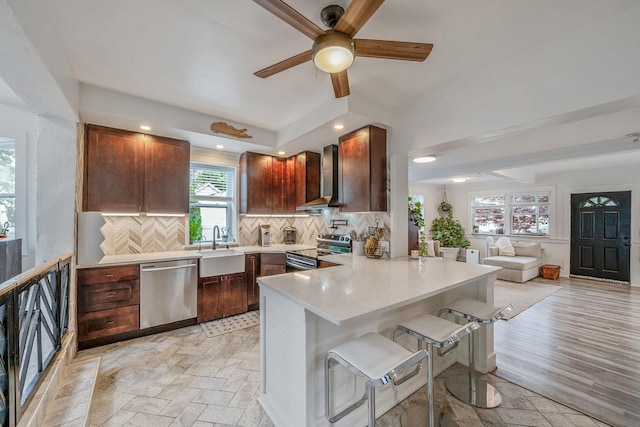 29 Montauk St, Selden, NY 11784 - kitchen featuring stainless steel appliances, wall chimney exhaust hood, a ceiling fan, a peninsula, and tasteful backsplash