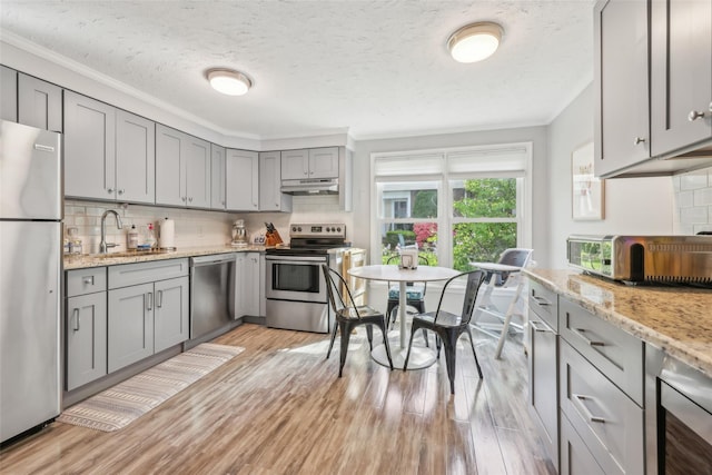 7 Washington Mews Unit 7, Port Chester, NY 10573 - kitchen with appliances with stainless steel finishes, gray cabinets, ornamental molding, under cabinet range hood, and backsplash