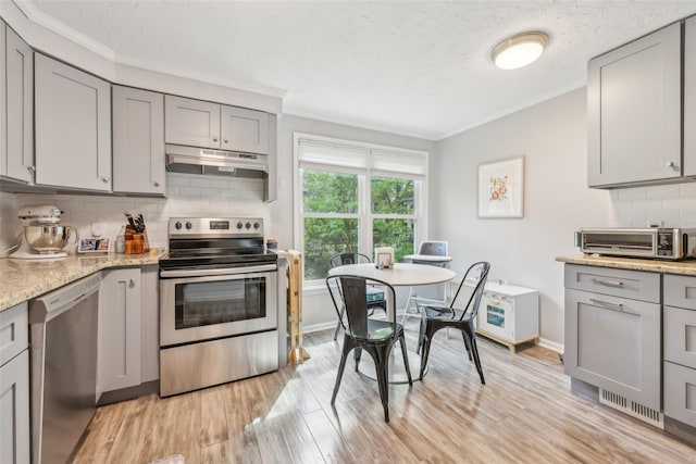 7 Washington Mews Unit 7, Port Chester, NY 10573 - kitchen featuring stainless steel appliances, gray cabinets, under cabinet range hood, ornamental molding, and decorative backsplash