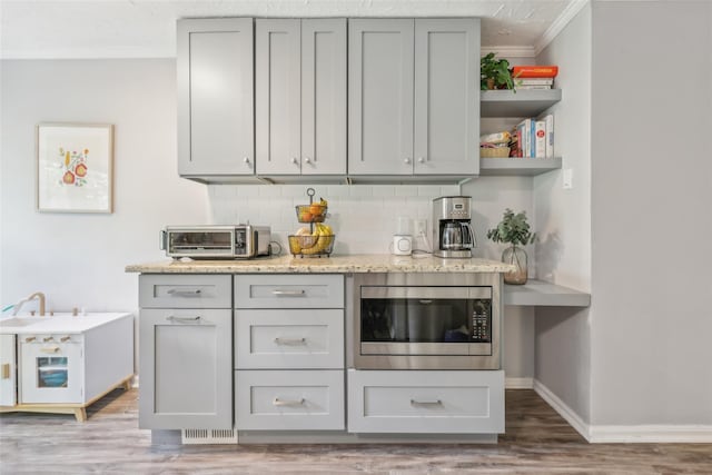 7 Washington Mews Unit 7, Port Chester, NY 10573 - kitchen with stainless steel microwave, ornamental molding, decorative backsplash, gray cabinetry, and wood finished floors