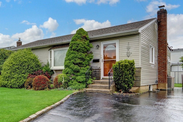 207 N 3rd St, Bethpage, NY 11714 - view of front of house with a front yard, a chimney, and cooling unit