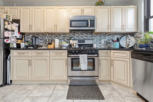 1 Jefferson Ave Unit B12, Rockville Centre, NY 11570 - kitchen with stainless steel appliances, cream cabinetry, dark countertops, decorative backsplash, and light marble finish flooring
