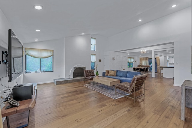 291 Starling Ct, Manhasset, NY 11030 - living room featuring a tiled fireplace, wood-type flooring, high vaulted ceiling, a chandelier, and recessed lighting