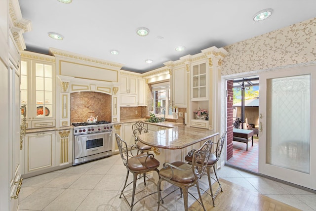 267 Dover St, Brooklyn, NY 11235 - kitchen with designer range, cream cabinetry, glass insert cabinets, light stone counters, and a breakfast bar