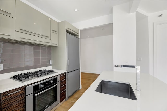 26-26 Jackson Ave Unit 402, Long Island City, NY 11101 - kitchen featuring stainless steel appliances, light countertops, light wood-style floors, backsplash, and a sink