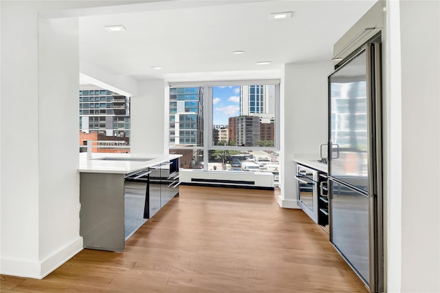 26-26 Jackson Ave Unit 402, Long Island City, NY 11101 - kitchen featuring stainless steel appliances, light wood-type flooring, light countertops, modern cabinets, and baseboards