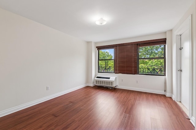 71-19 162nd St Unit 4E, Fresh Meadows, NY 11365 - spare room featuring dark wood-type flooring, a wall unit AC, and baseboards