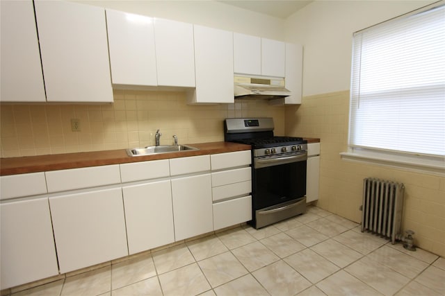 61-16 84th St, Middle Village, NY 11379 - kitchen with radiator heating unit, stainless steel range with gas cooktop, under cabinet range hood, a sink, and white cabinets