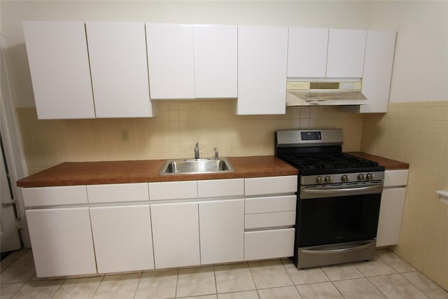61-16 84th St, Middle Village, NY 11379 - kitchen with under cabinet range hood, gas stove, a sink, tile walls, and white cabinetry