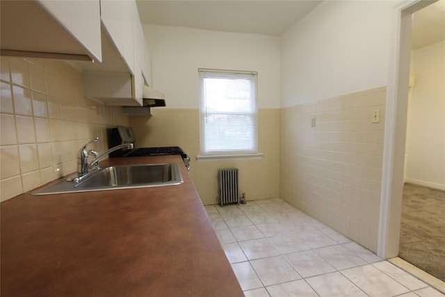 61-16 84th St, Middle Village, NY 11379 - kitchen featuring radiator, tile walls, stainless steel range with gas stovetop, a sink, and light tile patterned floors