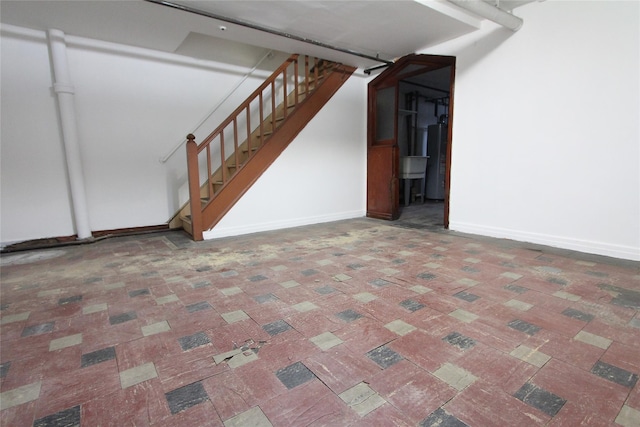 61-16 84th St, Middle Village, NY 11379 - finished below grade area with stairs, baseboards, water heater, and brick patterned flooring