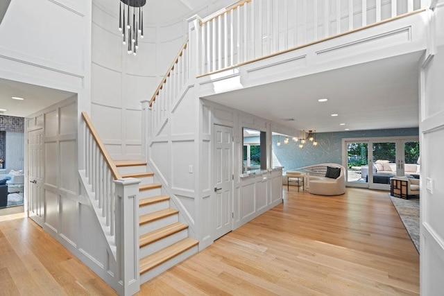 2 Field Ln, Roslyn Heights, NY 11577 - staircase featuring a towering ceiling, a decorative wall, wood finished floors, and a chandelier