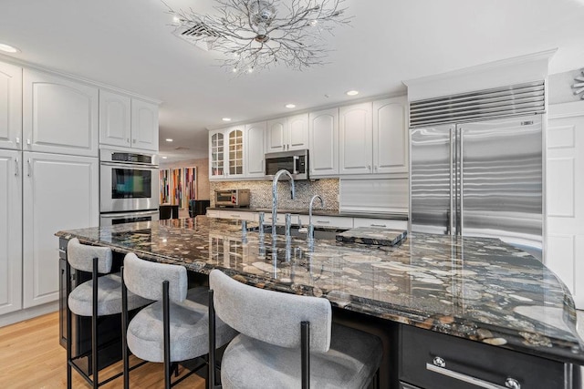 2 Field Ln, Roslyn Heights, NY 11577 - kitchen featuring stainless steel appliances, a kitchen bar, white cabinets, decorative backsplash, and recessed lighting