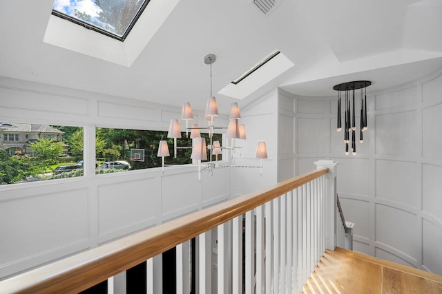2 Field Ln, Roslyn Heights, NY 11577 - hallway with a decorative wall, a skylight, an upstairs landing, healthy amount of natural light, and a chandelier