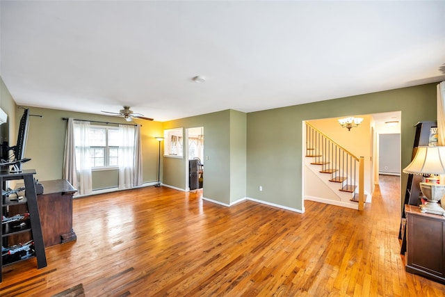 301 Maple Ave, Patchogue, NY 11772 - unfurnished living room with stairs, light wood-style flooring, a chandelier, and a ceiling fan
