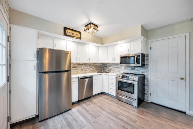 301 Maple Ave, Patchogue, NY 11772 - kitchen with stainless steel appliances, decorative backsplash, light wood-type flooring, white cabinetry, and light countertops