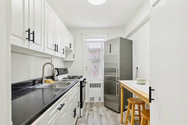 88-09 35th Ave Unit 5K, Jackson Heights, NY 11372 - kitchen featuring freestanding refrigerator, range with gas stovetop, radiator heating unit, a sink, and light wood-style flooring