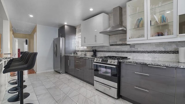 3217 Tenbroeck Ave, Bronx, NY 10469 - kitchen with wall chimney exhaust hood, stainless steel appliances, modern cabinets, light stone counters, and tasteful backsplash