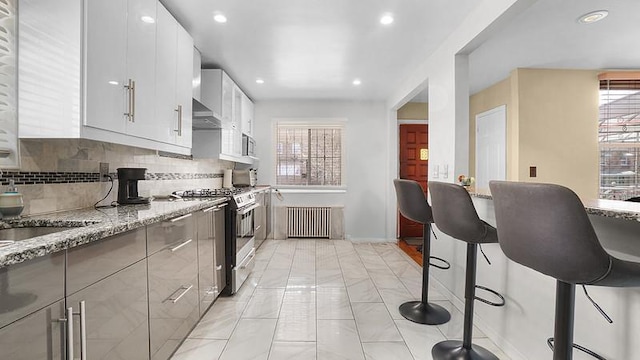 3217 Tenbroeck Ave, Bronx, NY 10469 - kitchen with radiator, stainless steel gas range oven, plenty of natural light, light stone countertops, and recessed lighting