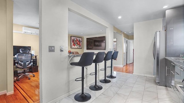 3217 Tenbroeck Ave, Bronx, NY 10469 - kitchen with a wall unit AC, freestanding refrigerator, a breakfast bar area, baseboards, and recessed lighting