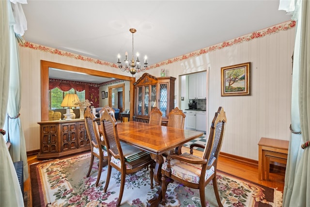 45-31 169th St, Flushing, NY 11358 - dining area featuring wood finished floors, a chandelier, wallpapered walls, and baseboards