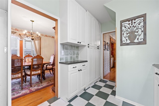 45-31 169th St, Flushing, NY 11358 - kitchen with a chandelier, light flooring, white cabinets, dark countertops, and hanging light fixtures