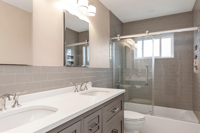 19 Alan Ct, Plainview, NY 11803 - bathroom featuring double vanity, toilet, bath / shower combo with glass door, tile walls, and decorative backsplash