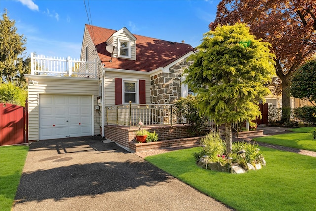 597 Stratford Rd, Baldwin, NY 11510 - cape cod-style house featuring asphalt driveway, a garage, stone siding, a front yard, and a balcony