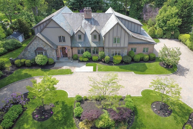 220 Elderfields Rd, Manhasset, NY 11030 - tudor-style house with stone siding, a chimney, a front lawn, and board and batten siding