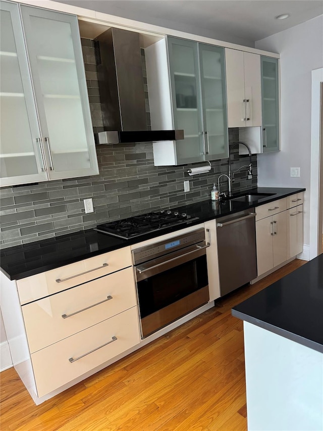 143 Garth Rd Unit 3Ef, Scarsdale, NY 10583 - kitchen featuring appliances with stainless steel finishes, wall chimney exhaust hood, light wood finished floors, decorative backsplash, and dark countertops