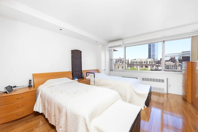 215 Park Row Unit 8B, New York Manhattan, NY 10038 - bedroom with radiator heating unit, a wall mounted air conditioner, and wood finished floors