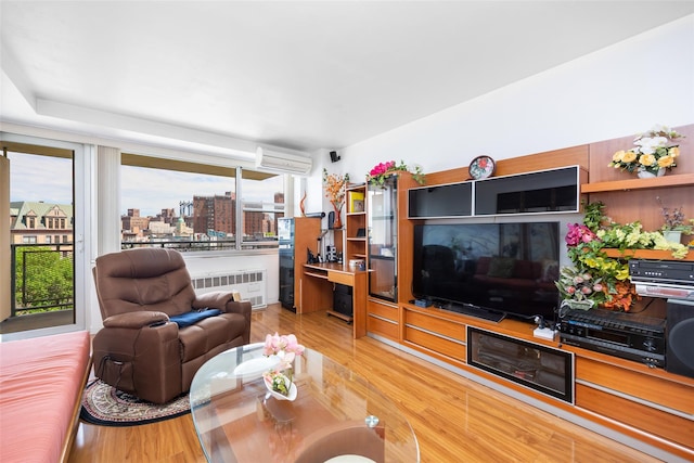 215 Park Row Unit 8B, New York Manhattan, NY 10038 - living area featuring radiator, a wall mounted air conditioner, wood finished floors, and plenty of natural light