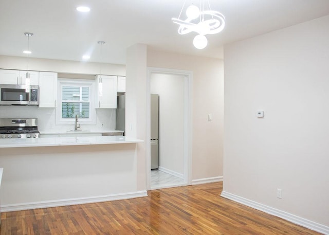 11 Shine Pl, Valley Stream, NY 11581 - kitchen featuring appliances with stainless steel finishes, light countertops, white cabinetry, wood finished floors, and recessed lighting