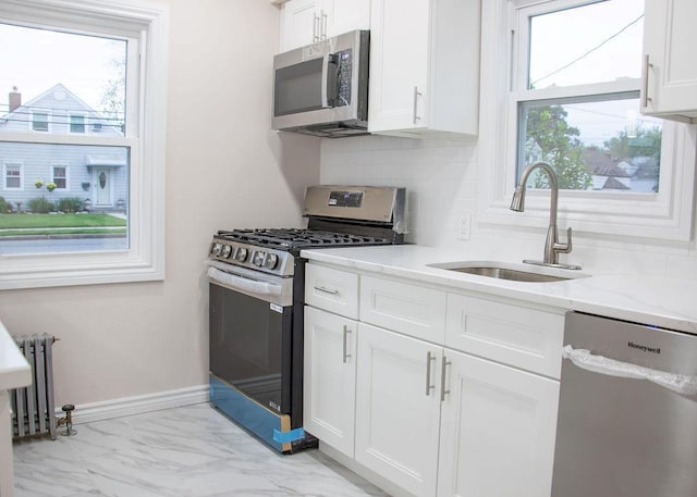 11 Shine Pl, Valley Stream, NY 11581 - kitchen with appliances with stainless steel finishes, a sink, radiator, white cabinetry, and tasteful backsplash