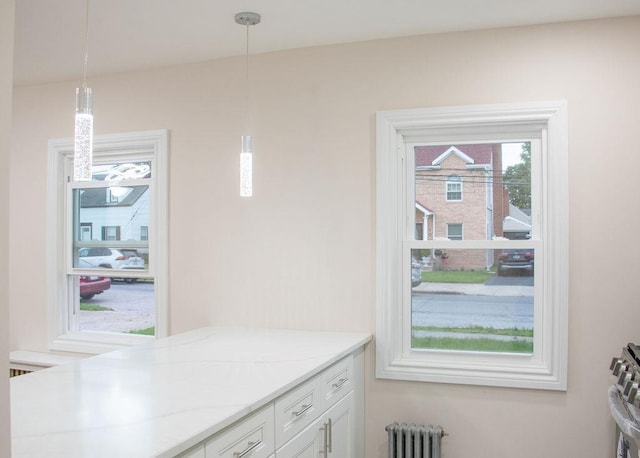 11 Shine Pl, Valley Stream, NY 11581 - kitchen with radiator heating unit, white cabinets, hanging light fixtures, and light stone counters