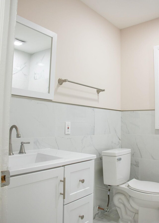 11 Shine Pl, Valley Stream, NY 11581 - half bath featuring tile walls, vanity, toilet, and a wainscoted wall