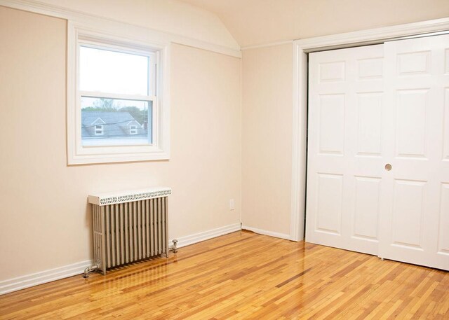 11 Shine Pl, Valley Stream, NY 11581 - unfurnished bedroom featuring radiator heating unit, light wood finished floors, lofted ceiling, baseboards, and a closet