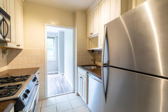 240 Garth Rd Unit 2G2, Scarsdale, NY 10583 - kitchen with stainless steel appliances, a sink, dark countertops, decorative backsplash, and light tile patterned floors