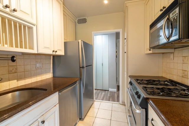 240 Garth Rd Unit 2G2, Scarsdale, NY 10583 - kitchen featuring stainless steel appliances, backsplash, dark stone countertops, light tile patterned floors, and a sink