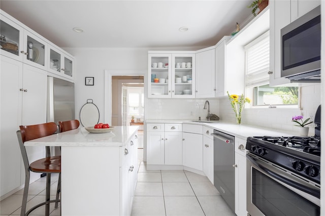 43 W 4th St, Locust Valley, NY 11560 - kitchen featuring stainless steel appliances, a kitchen bar, a sink, light tile patterned floors, and backsplash