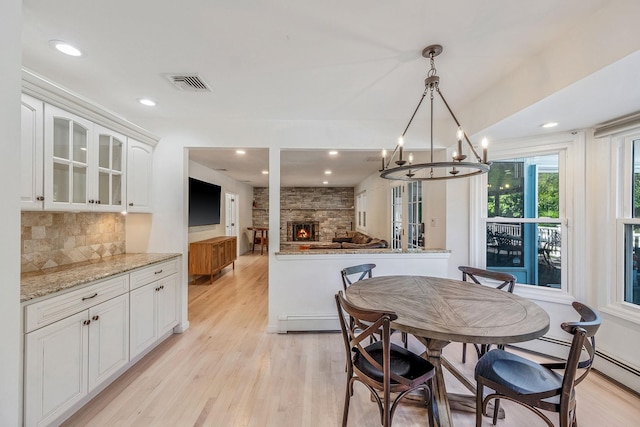 20 Vineyard Way, Mount Sinai, NY 11766 - dining space with light wood-style flooring, a stone fireplace, a chandelier, recessed lighting, and a baseboard heating unit