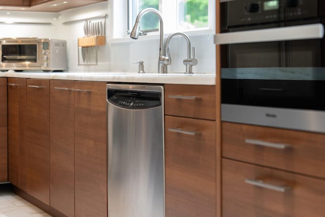 43 Random Farms Cir, Chappaqua, NY 10514 - kitchen with stainless steel appliances, brown cabinets, modern cabinets, light countertops, and light tile patterned flooring