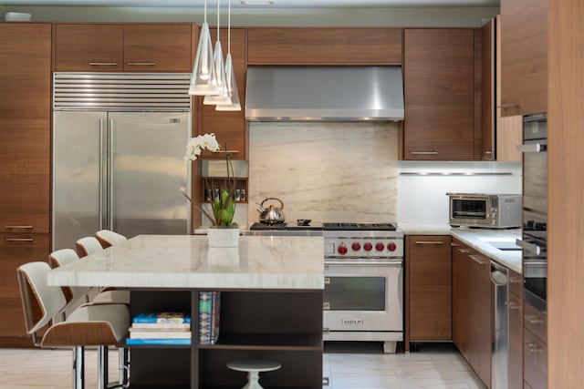 43 Random Farms Cir, Chappaqua, NY 10514 - kitchen featuring wall chimney range hood, high quality appliances, pendant lighting, and brown cabinets