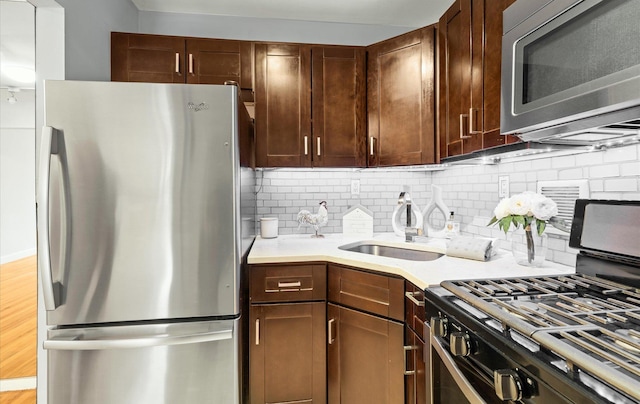 42-30 Douglaston Pkwy Unit 7H, Douglaston, NY 11363 - kitchen with stainless steel appliances, tasteful backsplash, a sink, light countertops, and wood finished floors
