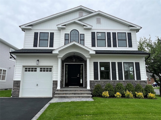 228 Latham Rd, Mineola, NY 11501 - craftsman-style house featuring stone siding, a front yard, a garage, and asphalt driveway
