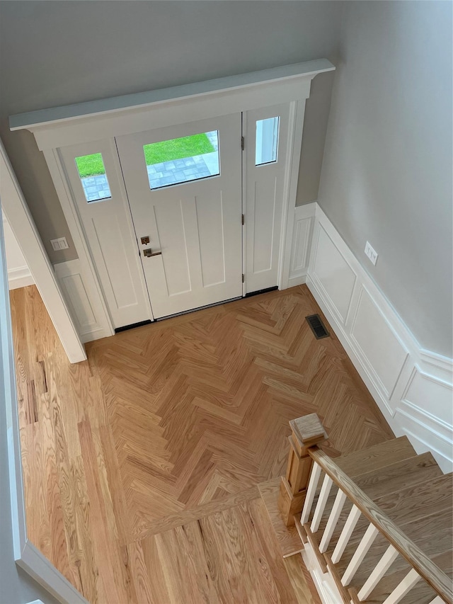 228 Latham Rd, Mineola, NY 11501 - entryway with a decorative wall, wainscoting, and stairs